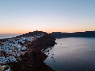 Aerial drone shot of the Santorini caldera at sunrise. Beautiful quiet morning with calm waters and the iconic white houses of Santorini. 
