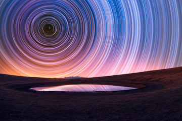 Beautiful night landscape, old volcano, crater lake. The colorful star trails on the sky. Night...