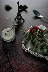 Flat lay still life of vintage antique decorative items with plant, berry, candle, and silver plate. Dark wooden background for festive christmas use with copy space.
