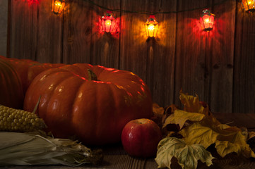 Composition for Thanksgiving. Pumpkin, corn cobs, apple, autumn leaves, colorful lanterns on a...