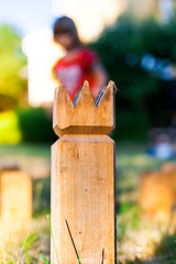 Kubb König aus Holz. Wikingerschach. Garten Wurfspiel.Kubb König mit Kind im Hintergrund. Child playing Kubb.
