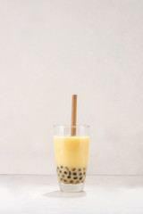 Bubble boba tea with milk and tapioca pearls in glass on white background