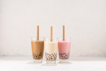 Various Bubble Tea in glasses with drink straws on white background