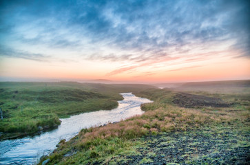 Iceland river at sunset with clouds in the red sky