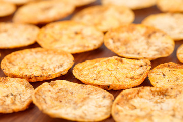 Close up of organic, crispy, baked, whole grain rice chips with tomato and paprika spices. Gluten free healthy snack on a wooden background.