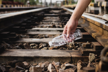 The hands of men are picking up plastic junk at the railroad tracks, ideas about reducing global warming and reducing plastic waste.
