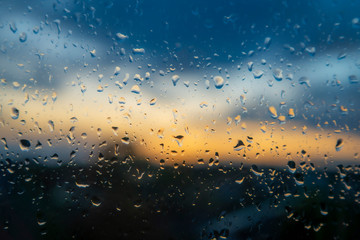Colorful sunset through wet window glass