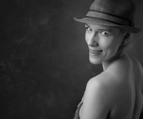 Attractive and slender woman in a hat shows her tongue.