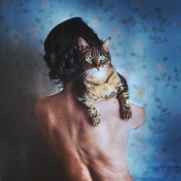 Rear view of woman carrying cat on her shoulder