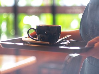The coffee shop staff hand is serving a cup of coffee to customers.