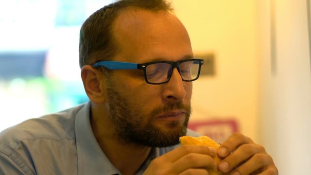 Young businessman eating sandwich in cafe