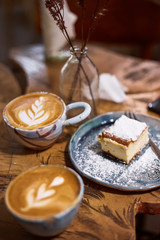 Cup of cappuccino coffee with cake on a rustic wooden table