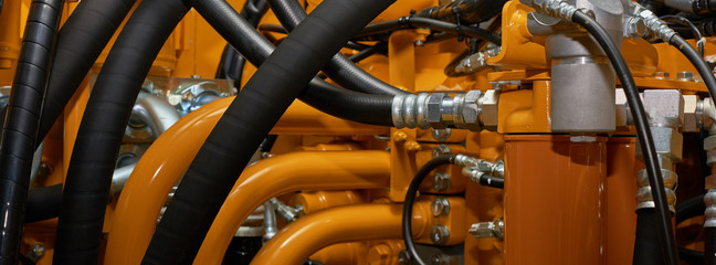 Banner with close up view of hydraulic pipes of heavy industry machine. Low key.