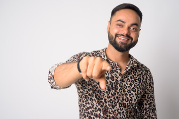 Portrait of happy young bearded Indian man pointing at camera