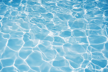 Fototapeta na wymiar Blue water surface with bright sun light reflections, water in swimming pool background