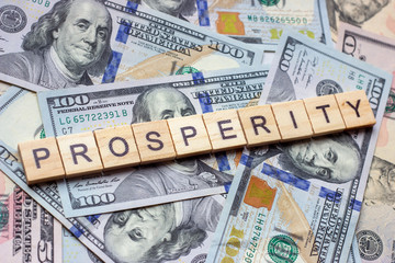 Fototapeta na wymiar The word prosperity on dollar usa background. Welfare, sufficiency and wealth concept.