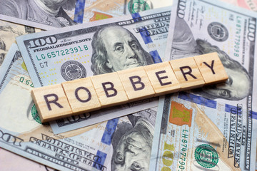 The word robbery on dollar usa background. Theft and stealing money concept