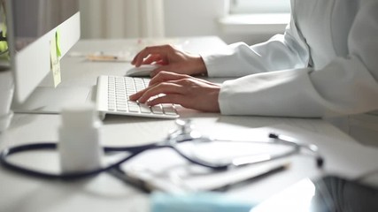 Hands of a doctor working on a computer keyboard. Close-up.