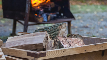Firewood in a box on the background of the brazier in which the fire burns_
