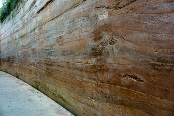Rustic brown cement wall and a walk path