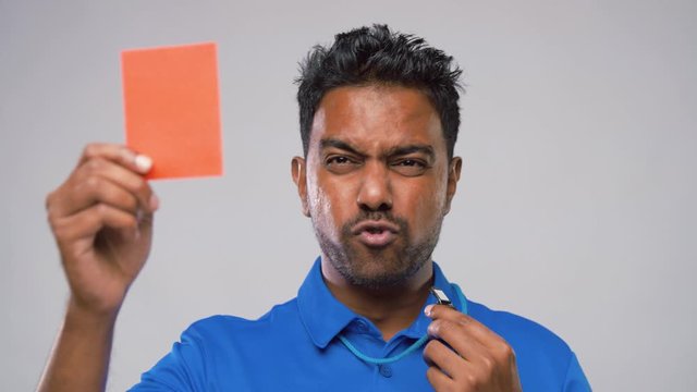 sport, caution, game and football concept - indian referee whistling and showing red penalty card