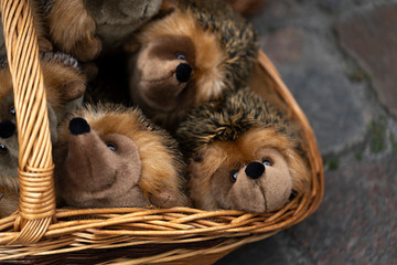 plush hedgehogs in a wicker basket outside. sale of soft toys