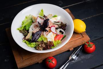 Tuna salad on a white plate on a wooden tray. 