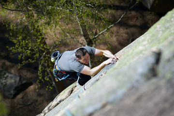 female rock climber climbs on a rocky wall. the view from the top