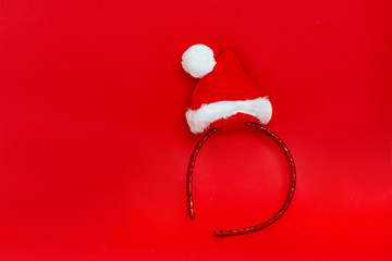 New Year. Red shiny hoop with Santa's mini hat, decoration on the head. isolated on a red background.