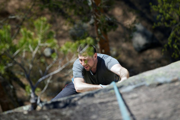 female rock climber climbs on a rocky wall. the view from the top