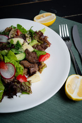 Liver salad with vegetables, on a white plate. 
