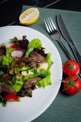 Liver salad with vegetables, on a white plate. 