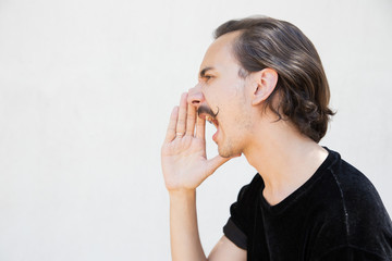 Excited guy announcing important news. Side of handsome young man with curly moustache keeping hand...