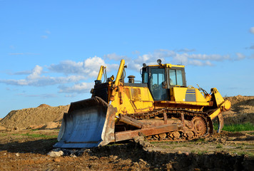 Obraz na płótnie Canvas Track-type bulldozer, earth-moving equipment. Land clearing, grading, pool excavation, utility trenching, utility trenching and foundation digging during of large construction jobs.