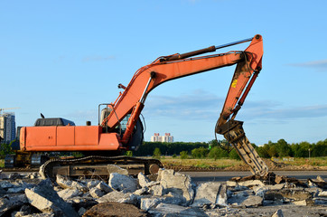 Crawler excavator with hydraulic hammer for the destruction of concrete and hard rock at the construction site. Replacing a concrete runway or road surface at an airport. Roadworks background - Image