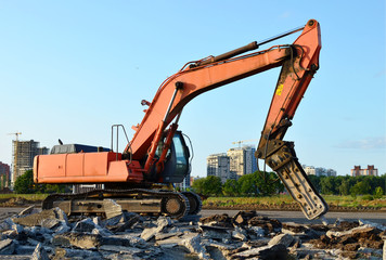 Fototapeta na wymiar Crawler excavator with hydraulic hammer for the destruction of concrete and hard rock at the construction site. Replacing a concrete runway or road surface at an airport. Roadworks background - Image