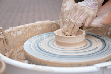 Hands forming clay on the pottery wheel