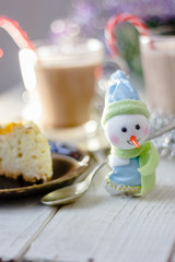 Winter snowman sitting near the plate with christmas pie