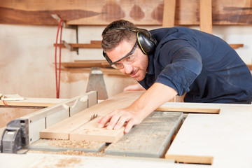 Mann als Tischler sägt konzentriert Holz