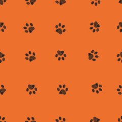 Fototapeta premium Black doodle paw prints with orange background seamless pattern. Happy Halloween background
