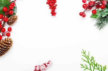 Holly ilex twigs and pinecones top view background. Decorative botanical frame with copyspace on white backdrop. Christmas, New Year composition with hoarfrost berries and fir branches