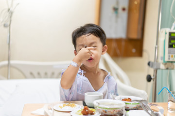A patient boy is eatting food while he sick in the hospital.