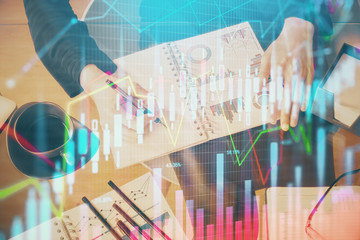 Double exposure of hands making notes with forex chart huds. Stock market concept.