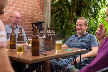Happy man smiling and looking at camera while having beer with friends