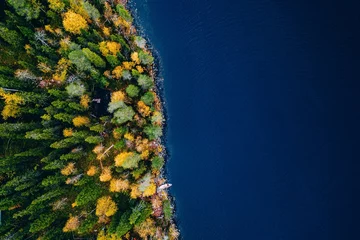 Luftaufnahme der Hütte im Herbstfarbenwald am blauen See im ländlichen Finnland © NBLX