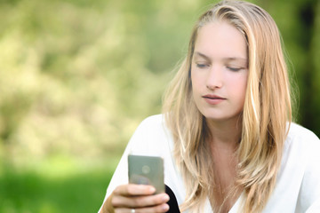 Young woman outdoors using a smartphone, green background