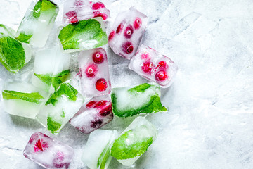 frozen red berries in ice cubes on stone background top view