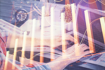 Double exposure of stock graph with businessman typing on computer in office on background. Concept of hard work.