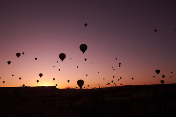 a lot of big air balloons in the sunrised sky over sandy hills