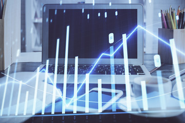 Stock market graph on background with desk and personal computer. Double exposure. Concept of financial analysis.